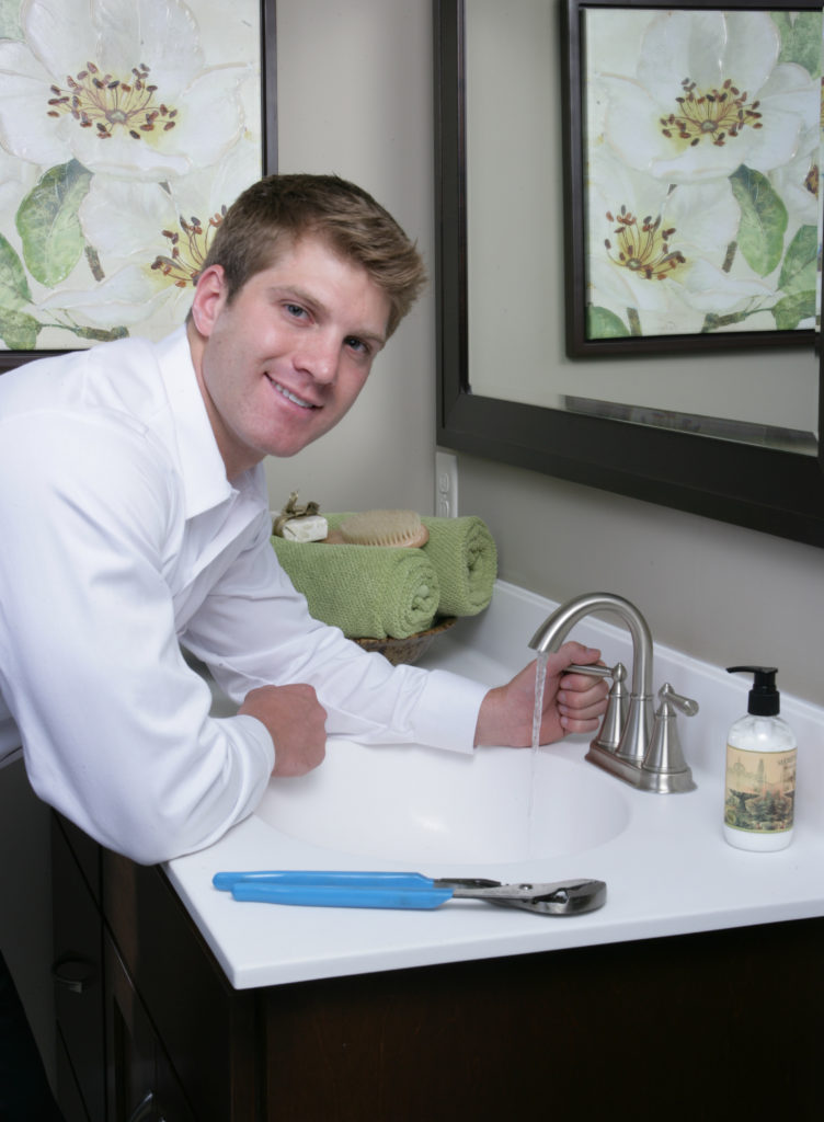 Plumber smiling while performing a plumbing repair in the bathroom of a home in Houston, TX