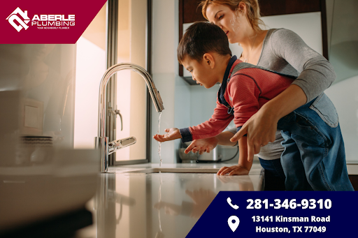 A mom and son using a kitchen sink.