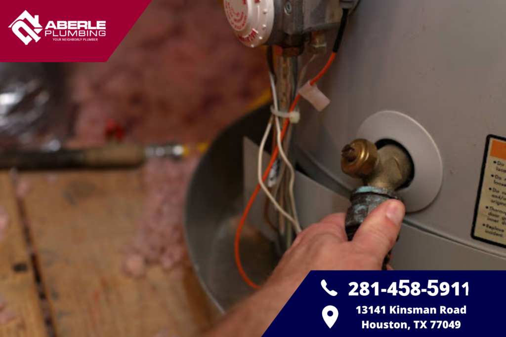 A hand grabbing a water heater drain valve.